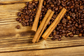 Coffee beans and cinnamon sticks on rustic wooden background. Top view
