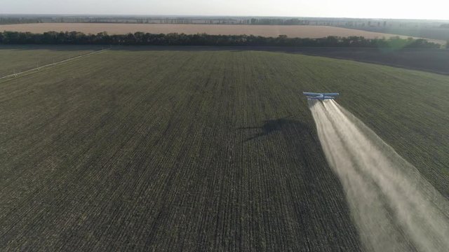 beautiful view of vintage airplane in Solar Beams flies over green Grain field and splashing chemicals against parasite into agriculture in aerial view