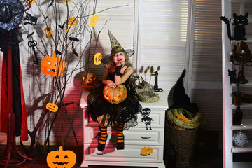 Little witch with Halloween decor. Kid in witch hat