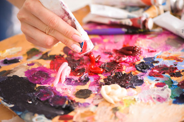 Closeup of paintbrush in woman hands mixing paints on palette