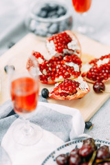 Summer picnic in nature, beautiful fruits and wine. Pomegranate, apples, pastries and bread on a blanket. Cheese and cherries in a beautiful design on the table