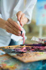 art, creativity and people concept - close up of artist with palette knife painting still life on easel at studio