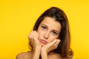 emotion face. sad depressed downcast gloomy low spirited woman. young beautiful brunette girl portrait on yellow background.