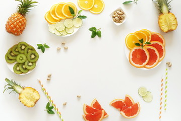 Summer tropical fruits composition top view background. . Pineapples, kiwi, lime, grapefruit, orange,  pistachios on white background. Summer food concept. Flat lay,  copy space
