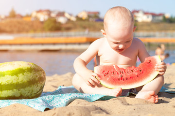 Little boy eating watermelon on the beach