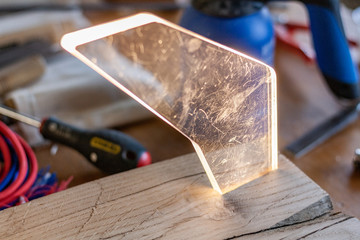 Wood and light, Eco-friendly woodworker's shop. Details and focus on the texture of the material, sawdust, and hands or lighting, while making a futuristic lamp. Mastering wood with peacefullness.