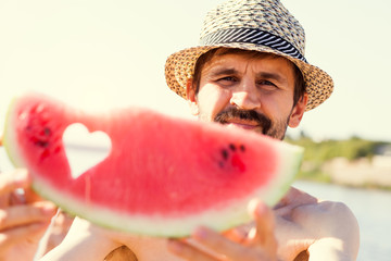 Young man with a watermelon on the beach