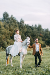 Obraz premium Wedding in American style, on a ranch with a horse. Walk couples in the fields at sunset, with friends and on horseback. Modern couple and ideas for the ceremony.