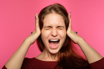 don't want to hear it. rejection refusal and denial. young woman covering ears with hands. portrait of a screaming girl with tightly shut eyes on blue background.