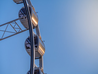 Low angle shot to a part of big wheel in playground park. Worm eye view Image of Ferris wheel. Uprise to look at a part of machine in sunny day. Take angle elevation to a beautiful blue sky.