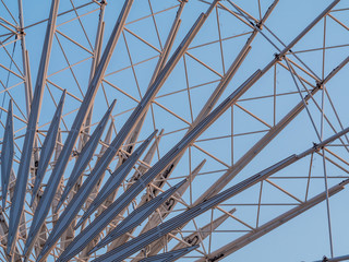 Low angle shot to a part of big wheel in playground park. Worm eye view Image of Ferris wheel. Uprise to look at a part of machine in sunny day. Take angle elevation to a beautiful blue sky.