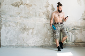 gym training break. man using mobile phone while resting from exercises.