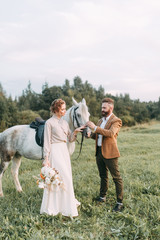 Wedding in American style, on a ranch with a horse. Walk couples in the fields at sunset, with...