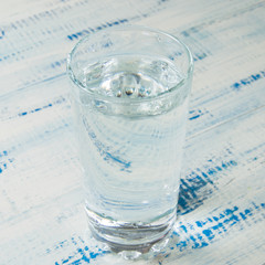 A glass of water on a wooden background.