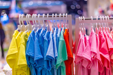 Colorful t-shirts children's wear on hang for sale in shop. Summer season children's clothes department store. Summer sale in shopping mall.
