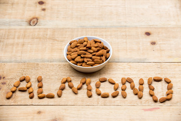 Almonds in a white cup rests on a wooden table