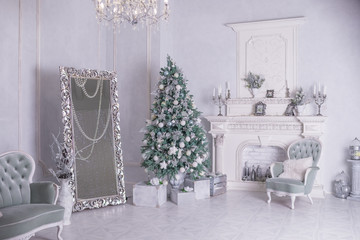 Decorated Christmas tree and gift boxes in living room.large white living room with a vintage furniture and a large Christmas tree with gifts and big mirror. Happy new year. Christmas morning in