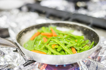Green beans and carrot fried together on silver pan