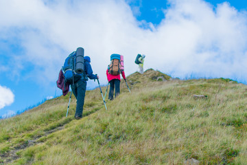 Obraz premium A group of people with backpacks hiking in the mountains.