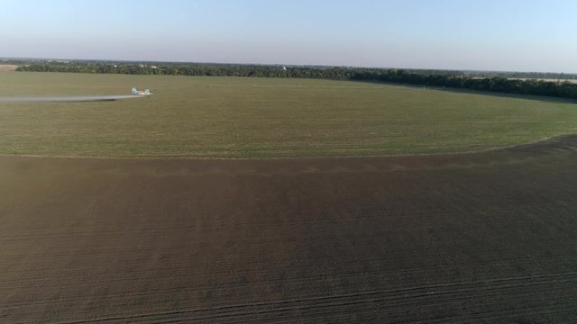farming, Agricultural Aviation flies over Grain field and splashing chemicals against pests in Top view of vintage propelled plane flies beautifully over green plantation
