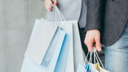 shopping for clothing. midseason store sale. cropped shot of man hand holding multiple bags.
