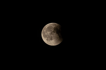 Partially eclipsed full moon, long shot, black sky