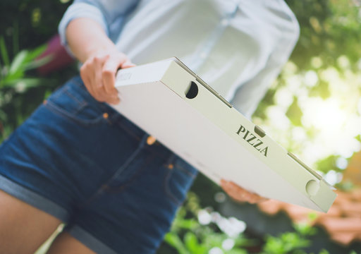 Pizza delivery woman holding pizza box.