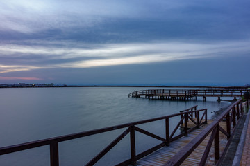 Obraz premium Long exposure of pier at sunrise with lake