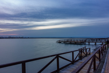 Long exposure of pier at sunrise with lake