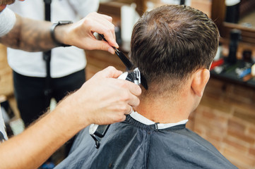 barber cutting hair with scissors. back view of man in barber shop