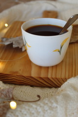 Fototapeta na wymiar Breakfast in the bed: Cup Coffee with Cozy winter home background. Cup of hot coffee on the wood tray on the bed.