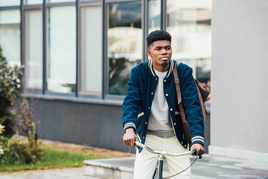handsome african american man riding bicycle in city