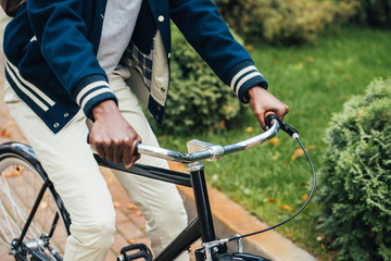 cropped view of african american man riding bicycle in park