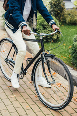 cropped view of stylish african american man riding bicycle on street