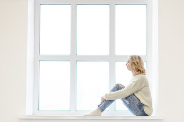 Young woman sitting in front of window.