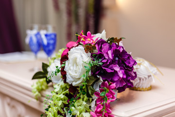 Stylish wedding decorarion of tender white, purple and pink flowers and two wine glasses