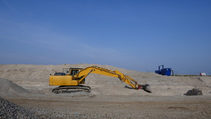 Big, yellow excavator in front of blue sky