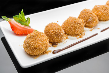 Delicious restaurant dessert with three scoops of fried ice cream topped with chocolate, served with whipped cream