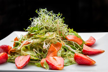 Strawberry, avocado, lettuce salad with cashew nuts on plate