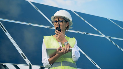 An engineer works with devices, standing on a roof near solar batteries. Alternative, green energy...