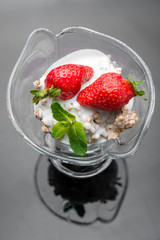 Healthy breakfast. Oatmeal granola crumble with rhubarb, fresh strawberries and blackberries, seeds and ice cream on marble white plate