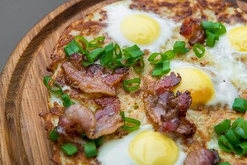 Plate with fried eggs, bacon, tomato and potato griddle cakes close up