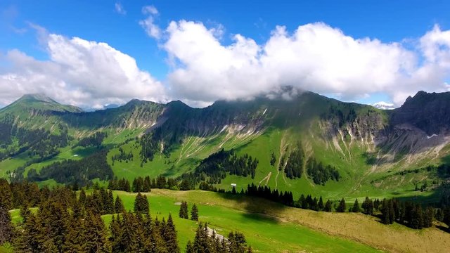 Aerial shot over Alpine landscape, Switzerland in spring
Forest and Alpages, summits in the background in the clouds