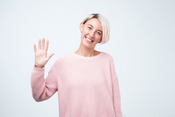 Portrait of a young woman in pink sweater smiling and saying hello © RealPeopleStudio