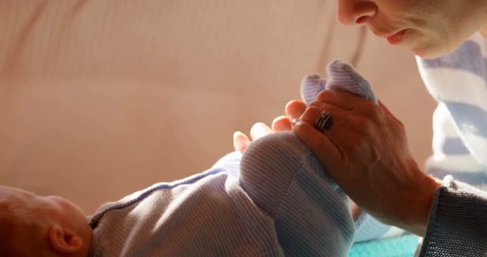 Mother playing with her baby boy feet in living room 4k