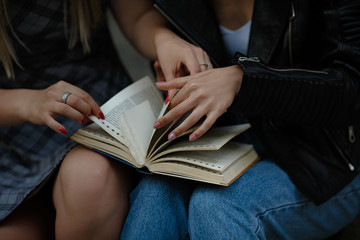 Cute lesbian couple read together. Sitting on bench and turning book pages. Samesex love.