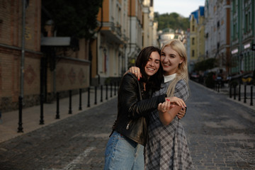 Two young lesbians with happy faces walking in the city. Having relations. Samesex love concept.