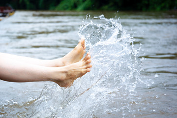 Girl enjoying with splashing water beside the river close up.