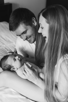 black and white picture of happy family playing with infant son in bed at home