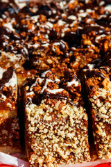 Sliced snickers cake close-up. Chocolate cake with peanuts on a tray